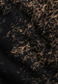 Textil con fondo negro y un patrón marrón moteado, con una textura suave y elementos de diseño irregulares.