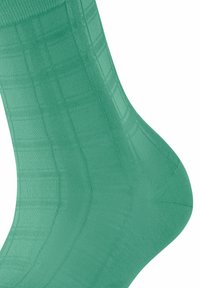 Groene katoenen sok met een gestructureerd ruitenpatroon. Het ontwerp heeft een geribde boord en een gladde afwerking.