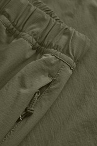 Olive zelená tkanina so šnúrkou v páse, plochou textúrou s jemnými pruhmi a bočnou vreckom s detailom na šnúrku.