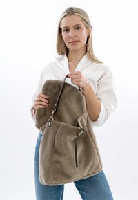 Borsa in pelliccia sintetica marrone con tracolla in pelle, caratterizzata da un'apertura ampia e una chiusura a cordoncino per una dimensione regolabile. Texture liscia.