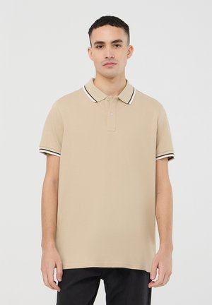 Polo beige con patta a due bottoni, colletto e polsini a righe nere e bianche, maniche corte, realizzato in morbido tessuto di cotone.