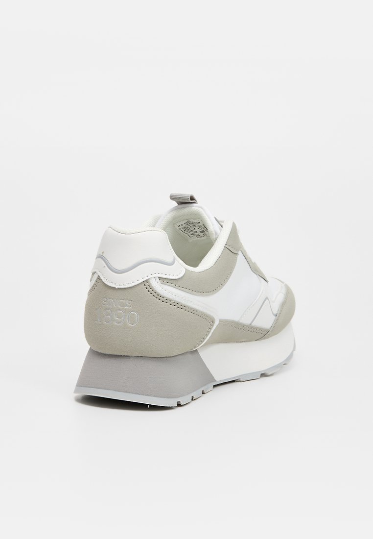 Zapatillas para hombre en gris y blanco, con un diseño elegante que combina materiales de ante y sintéticos, un talón texturizado y un detalle estampado que dice "Desde 1890".