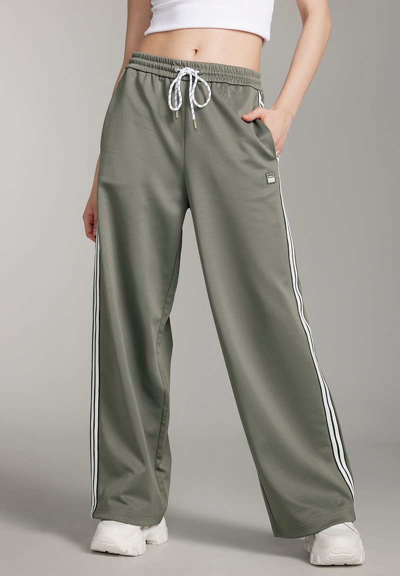 Olivgrüne, weit geschnittene Sweatpants aus glattem Stoff, mit weißen Seitenstreifen, elastischem Bund und Zugband sowie seitlichen Taschen.