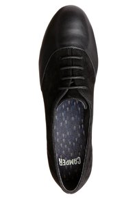 Chaussure noire à lacets avec bout lisse et côtés en daim, avec une semelle intérieure à motif portant le nom de la marque Camper.