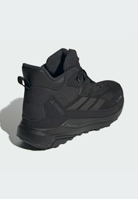 Čierne turistické topánky s hornej časťou z sieťoviny a syntetického materiálu, polstrovaný obvod a odolná gumová podrážka. Obsahuje textúrované akcenty a detaily loga.