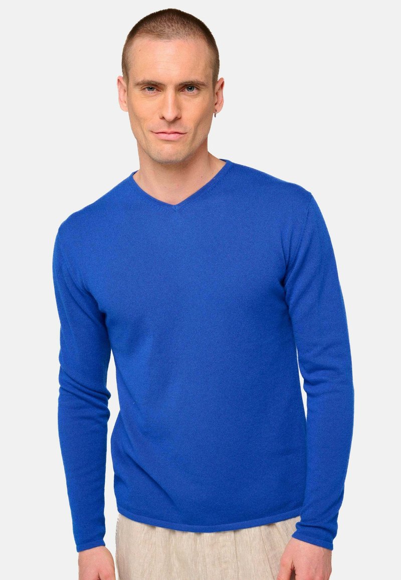 Pull bleu à manches longues avec un design en V, fabriqué en tissu tricoté lisse, présentant des manches ajustées et un ourlet légèrement arrondi.