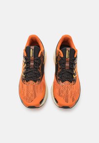 Las zapatillas de correr en naranja y negro presentan una parte superior de malla texturizada, una puntera reforzada y una suela acolchada con acentos en colores contrastantes.