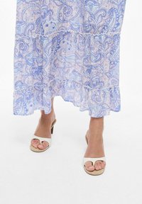 Abito maxi floreale paisley in azzurro chiaro e lavanda con orlo arricciato. Sandali beige con tacco, con anello per l'alluce e fascette lisce.