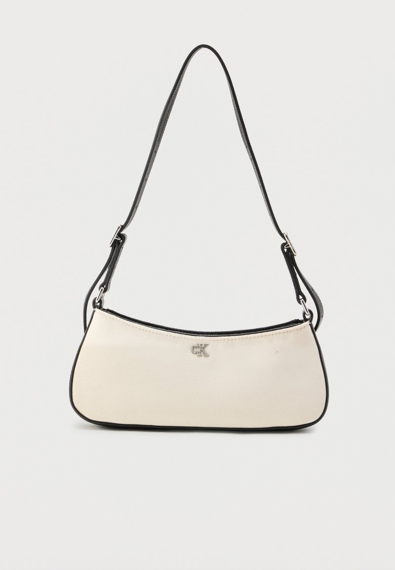 Sac à bandoulière couleur crème avec des accents noirs et un logo argenté, présentant un design incurvé et une finition en matériau lisse.