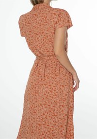 Ruskoinen oranssi mekko valkoisella kukkakuviolla, lyhyet hihat, kauluspainike ja vyötäröltä korostettu, virtaava, nilkkapituinen hame.