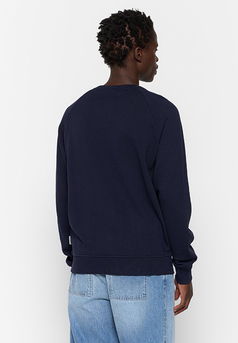 Felpa navy in cotone, con collo a girocollo, maniche raglan e polsini e orlo a costine. Texture liscia, branding minimale sul lato.