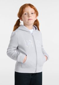 Light gray zip-up hoodie with a hood, front pockets, and floral-patterned embellishments on the chest. Soft, textured fabric. Black pants.