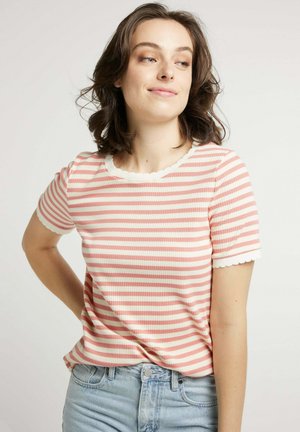 T-shirt à rayures côtelées en couleurs rose et crème, avec un col et des manches à volants, et une coupe décontractée. Associé à un jean bleu clair.