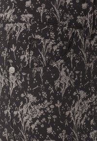 Czarna tkanina w kwiatowy wzór w odcieniach szarości, z kieszonką i metalowym guzikiem z boku.