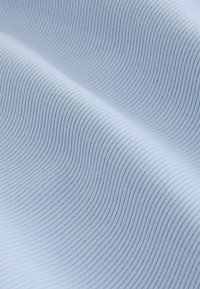 Tissu côtelé bleu clair avec de fines lignes verticales, délicatement plié créant des courbes et ombres douces.