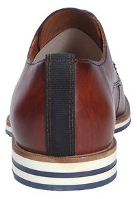Bruine leren schoen met een gladde afwerking, elastische accent bij de hiel en een gestreepte witte en marineblauwe zool. Rond ontwerp, minimale stiksels.