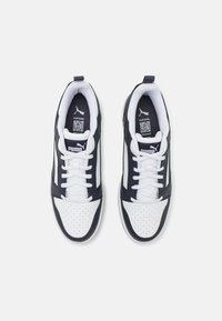 Schwarz-weiße Sportschuhe mit perforierter Zehenpartie, weißen Schnürsenkeln und PUMA-Logo auf der Zunge und der Seite. Glattes Leder mit Gummisohle.