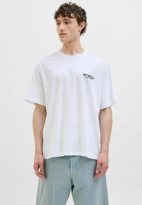 Hvid bomulds t-shirt med korte ærmer og løs pasform, med sort tekst "BOTANICA CITRUS SPECIES" på venstre bryst.