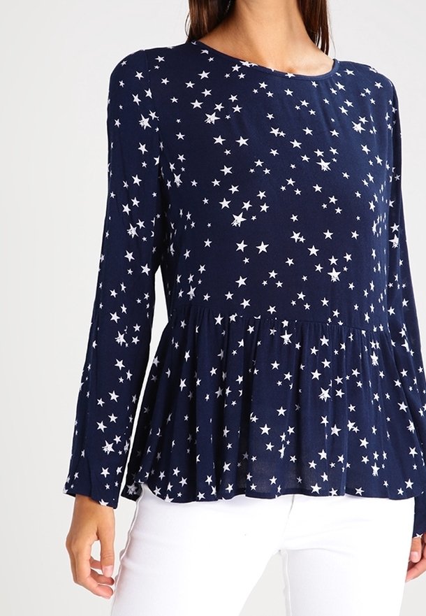 Maglietta a maniche lunghe blu navy con design peplum, caratterizzata da un motivo a stelle bianche su tutta la superficie e texture in tessuto morbido.
