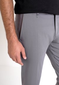 Pantalones gris ajustados hechos de un tejido de alta calidad, que presentan una textura suave, bolsillos frontales y un detalle de correa lateral ajustable.