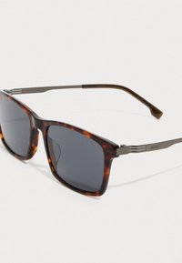 Kvadratiniai akinių rėmeliai, su vėžlio kiauto priekiu ir pilkais metaliniais šonais, ant kurių išgraviruota "BOSS" baltame fone.