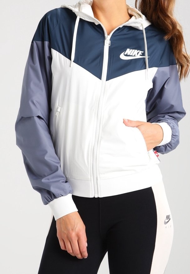 Lätt, färgblockerad Nike-jacka med en marinblå överdel, vit kropp och grå ärmar. Har en zippered framside och justerbar huva.