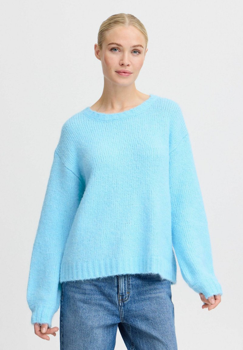 Maglione azzurro chiaro realizzato in materiale morbido e soffice. Presenta una vestibilità ampia, polsini a costine e un collo rotondo. Abbinato a jeans blu.