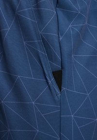 Tecido azul marinho com um padrão geométrico em lilás claro, apresentando um detalhe de costura e um pequeno bolso preto. Textura suave.