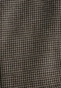 Houndstooth patterned fabric in brown and cream, featuring a textured weave, with a smooth finish and a regular grid structure.