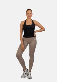 Čierny top na krk s voľným strihom, kombinovaný s tesnými béžovými legínami. Výrazný detail loga na tope a legínach. Dýchajúca tkanina.