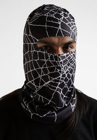 Pasamontañas negro con un patrón de telaraña blanca, que presenta aberturas para los ojos recortadas y orificios de ventilación. Hecho de tela elástica con una textura suave.