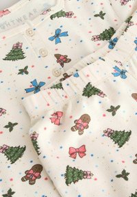 Kinder Baumwoll-Pajamas mit einem cremefarbenen Hintergrund und bunten Drucken von Weihnachtsbäumen, Schleifen und Lebkuchenfiguren. Mit Rippstruktur.