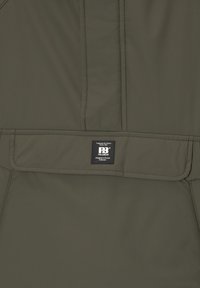 Veste vert foncé avec une poche à rabat horizontale affichant une étiquette noire Pull&Bear cousue au centre.