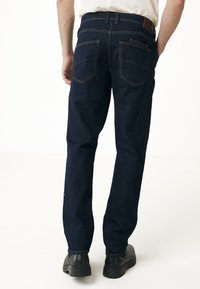 Mörkblå denimjeans med rak passform, med bakfickor, orange sömmar och en läderlapp vid midjan.