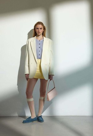 White oversized blazer over a gray button-up top, yellow mini skirt, light blue shoes, and a pink handbag. Smooth textures and distinct colors.