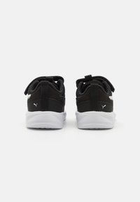 Chaussures de sport noires avec une tige en tissu texturé, semelle blanche et languettes de tirage prononcées au talon. Comprend un petit logo sur le côté.
