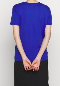 Niebieska koszulka z krótkim rękawem wykonana z bawełny, z okrągłym dekoltem i lekko luźnym krojem. Widok z tyłu nie pokazuje żadnych grafik ani ozdób.