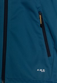 Giacca softshell di colore verde scuro con zip nera, dotata di un inserto giallo e testo del logo bianco. Tessuto morbido, design aderente.