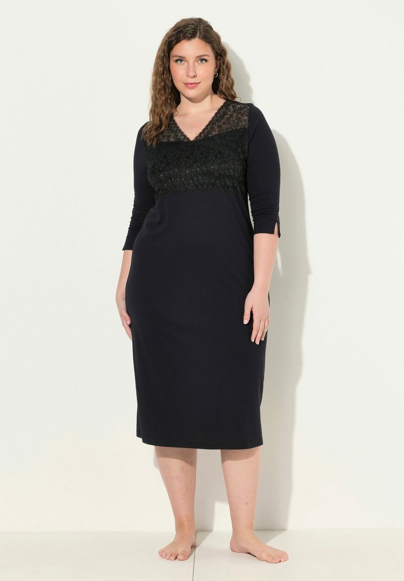 Abito nero a maniche lunghe con dettagli in pizzo sul corpetto a scollo a V. Tessuto morbido e elasticizzato; silhouette aderente; design al ginocchio.