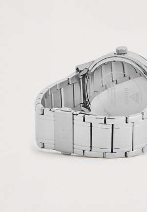 Montre en acier inoxydable argenté avec un bracelet poli, dotée d'un boîtier rond, d'une fermeture à clapet et d'un logo en relief sur le bracelet.