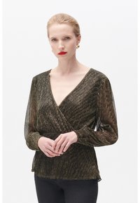 Blusa nera metallica avvolgente con maniche lunghe trasparenti, scollatura a V, tessuto texturizzato e sottili dettagli dorati, abbinata a pantaloni neri aderenti.