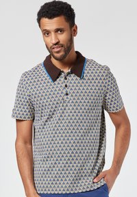 Lyhythihainen polo-paita, jossa on sinivalkoinen kuvioitu kangas, ruskeat kaulukset sinisillä yksityiskohdilla ja nappikiinnitys edessä.