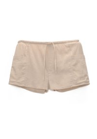 Short beige clair avec une taille élastique, un cordon de serrage et deux poches latérales. Le tissu semble doux avec une texture lisse.