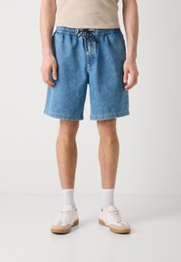 Shorts en denim bleu clair avec une taille élastique et un cordon noir réglable, présentant une coupe décontractée et un ourlet retroussé.