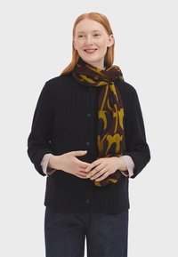 Navy jacket with vertical stripes and buttons, paired with a patterned yellow and burgundy scarf. Fabric appears soft and textured.