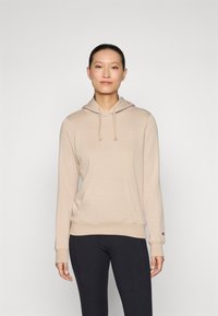 Hoodie beige clair avec une poche avant et une capuche à cordon. Présente un petit logo sur la poitrine. Tissu doux, manches et ourlets côtelés.
