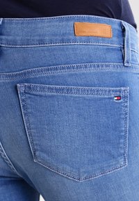 Blå denimjeans med en bakficka. Har en brandpatch i beige läder och subtila sömnadsdetaljer. Mjuk känsla och standard passform.