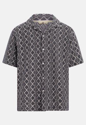 Chemise à manches courtes avec boutons, motif géométrique losange noir et blanc, col évasé, taille moyenne.