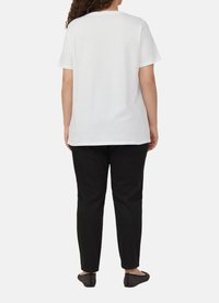 Witte kortegem t-shirt van katoen, gecombineerd met zwarte broek. De outfit wordt compleet gemaakt met zwarte platte schoenen met studded accenten.