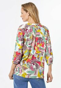 Dreiviertel-Ärmel Bluse mit einem mehrfarbigen Blumen- und geometrischen Muster. Der Stoff ist leicht, hat eine lockere Passform und eine gefaltete Rückendetail.